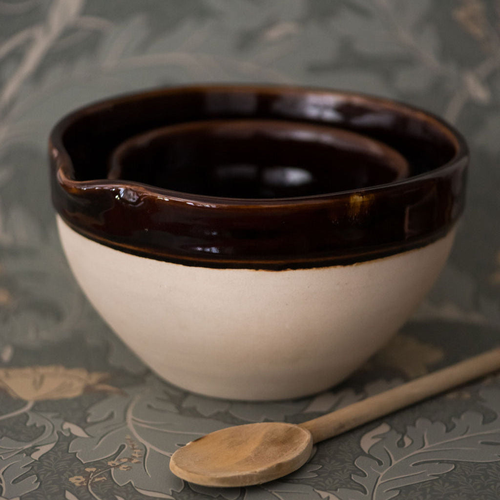 A beige and brown Heritage Stoneware large bowl with a wooden spoon, placed on a patterned fabric.